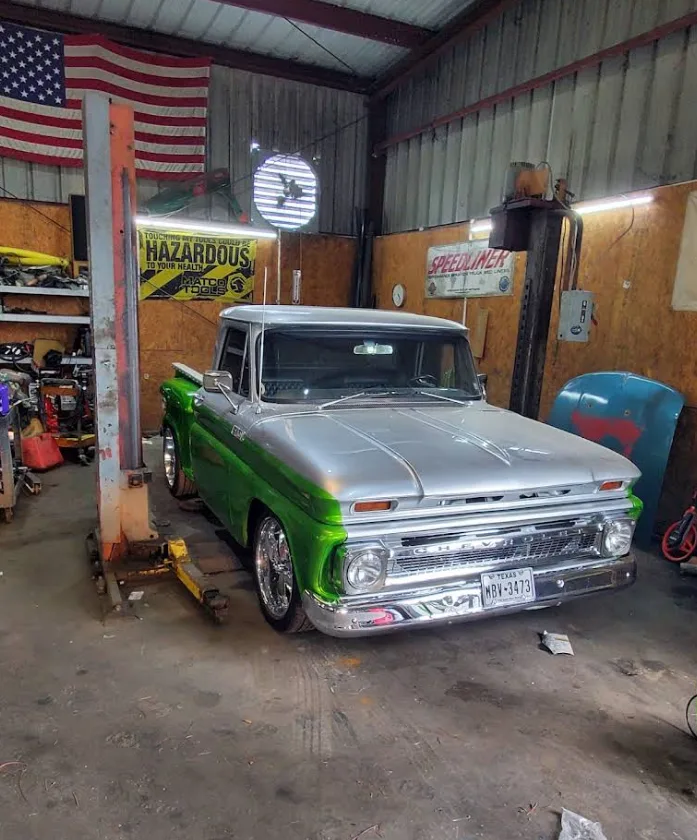 A green and silver Chevy C10 in an Area 51 Auto service bay